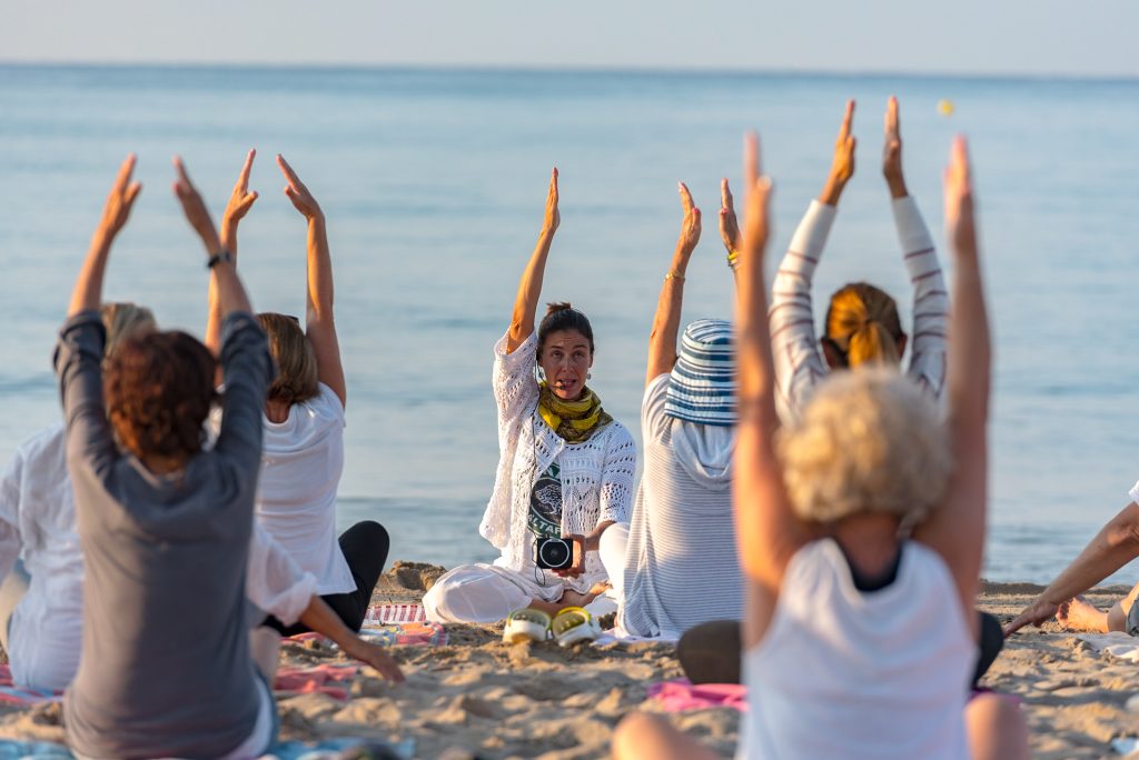 Yoga instructor leading a group session at sunset on the beach - Sharon Carr Travel, Dallas 
