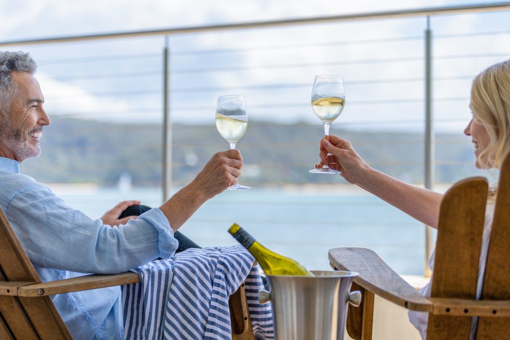 Mature couple drinking wine out on the deck. - Sharon Carr Travel