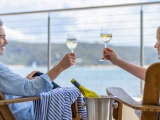 Mature couple drinking wine out on the deck. - Sharon Carr Travel