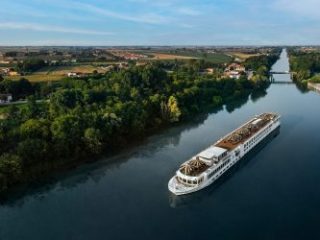 Uniworld river cruise ship sailing down a river in Europe - Sharon Carr Travel