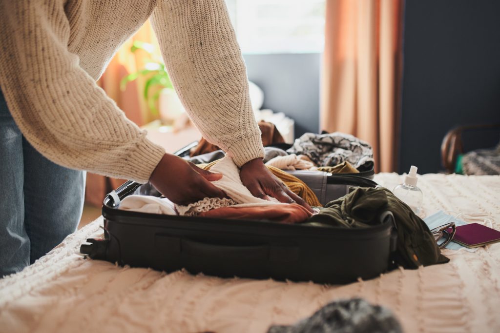 A woman packing her things into a suitcase at home before travelling - Sharon Carr Travel