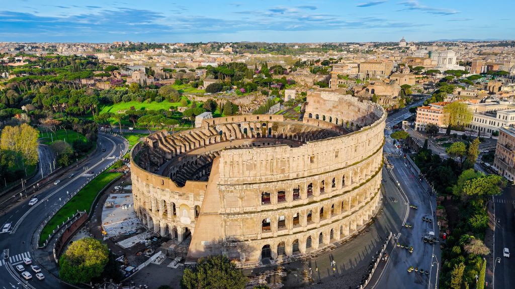 Aerial view of the ancient Colosseum in Rome with panoramic cityscape, iconic Roman amphitheater from different angles including top-down detail, Historical architecture and tourism concept for editorial and travel design - Sharon Carr Travel